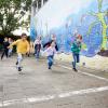 Kinderen rennen buiten op het schoolplein langs een muurschildering